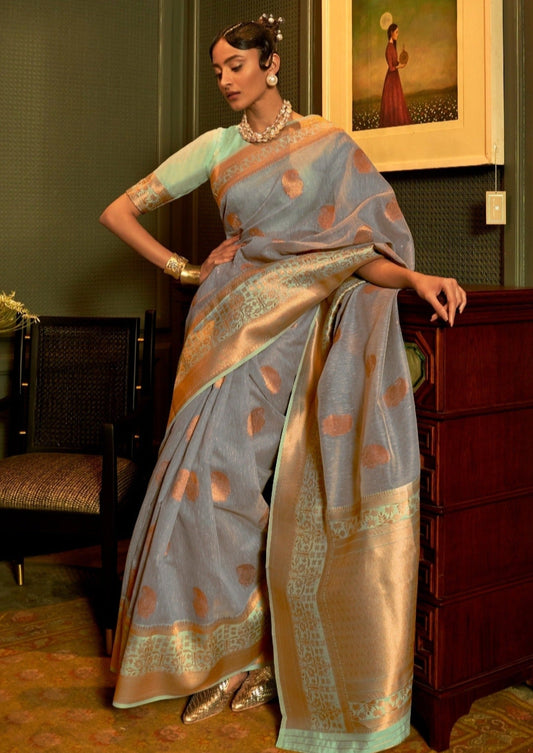 Pure linen handloom saree in grey and mint green color combination showcased on a woman standing in a traditional indian room.