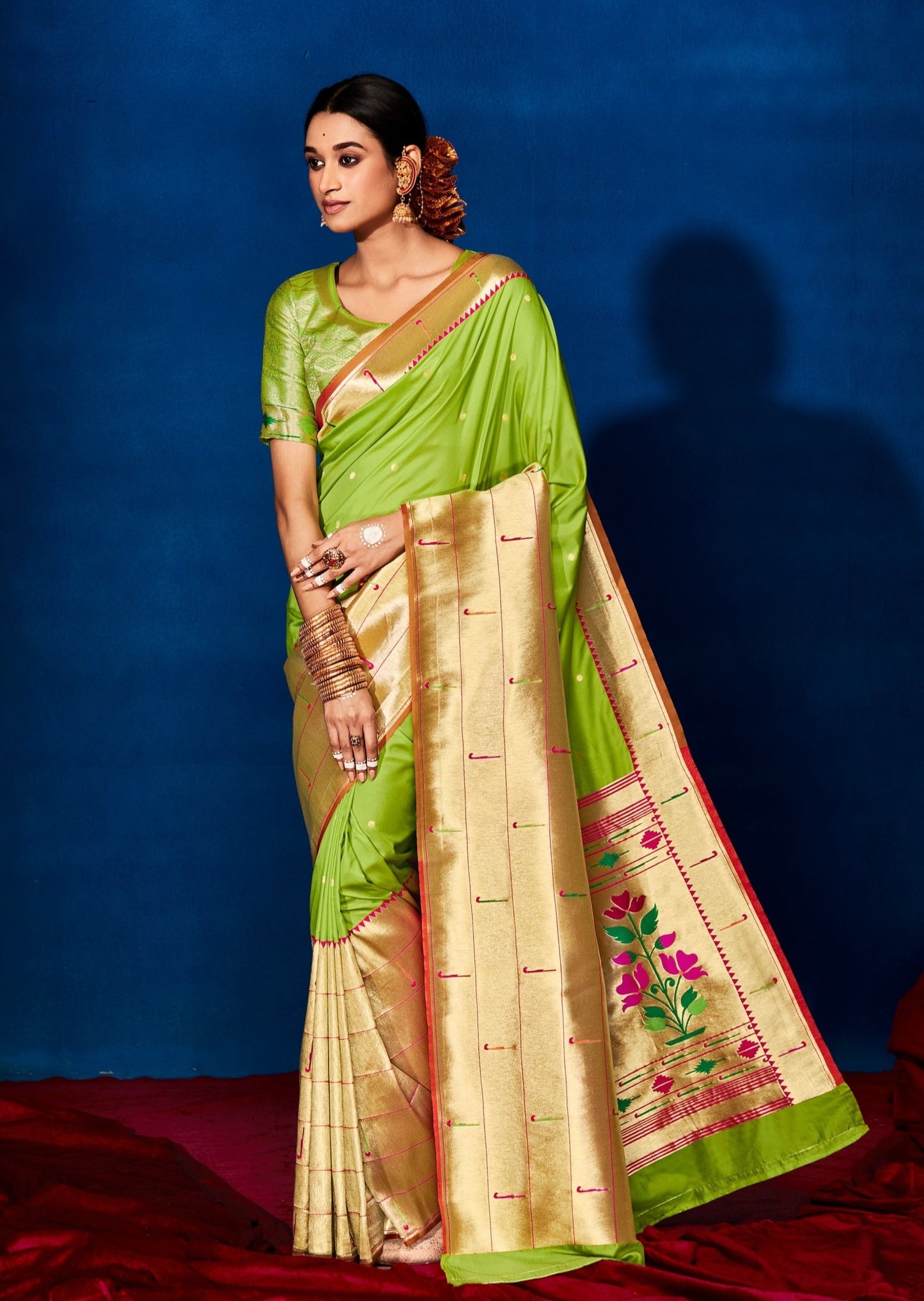 Woman in green silk saree standing on red carpet