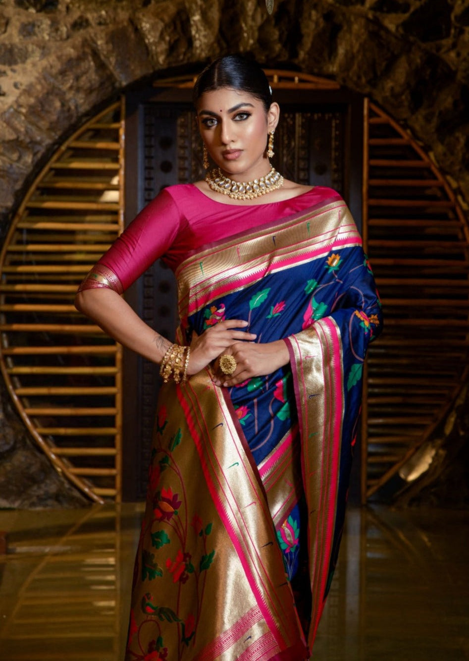 Woman in royal blue paithani saree and pink blouse.