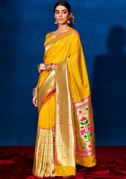 Woman standing in Yellow Paithani saree in front of a blue background
