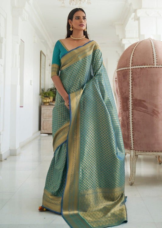 Kanjivaram silk handloom sarees online in turquoise blue color featuring gold zari weaving, worn by a woman.