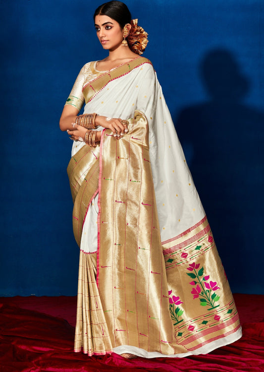 Woman standing in front of blue wall in a white silk saree